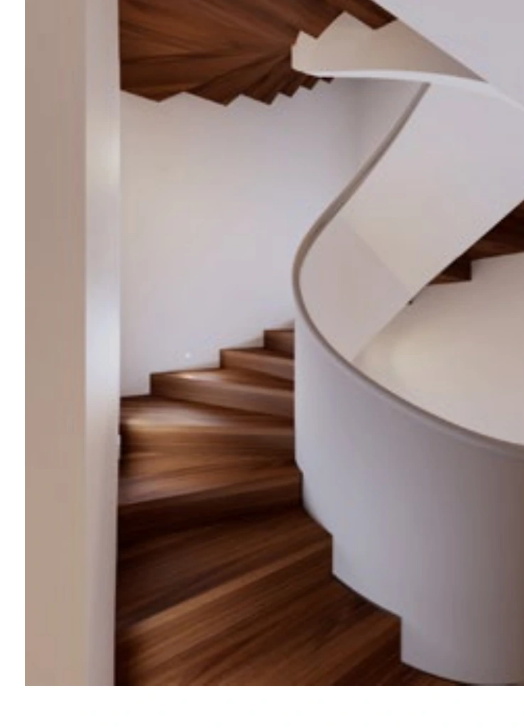 The sculptural walnut-wrapped stair connects four floors.